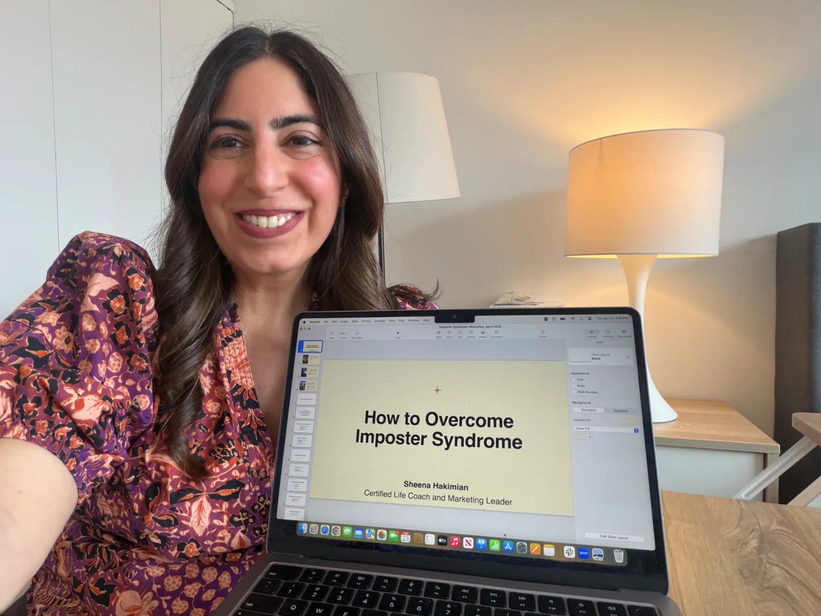 Sheena holding a laptop showing her imposter syndrome workshop slides
