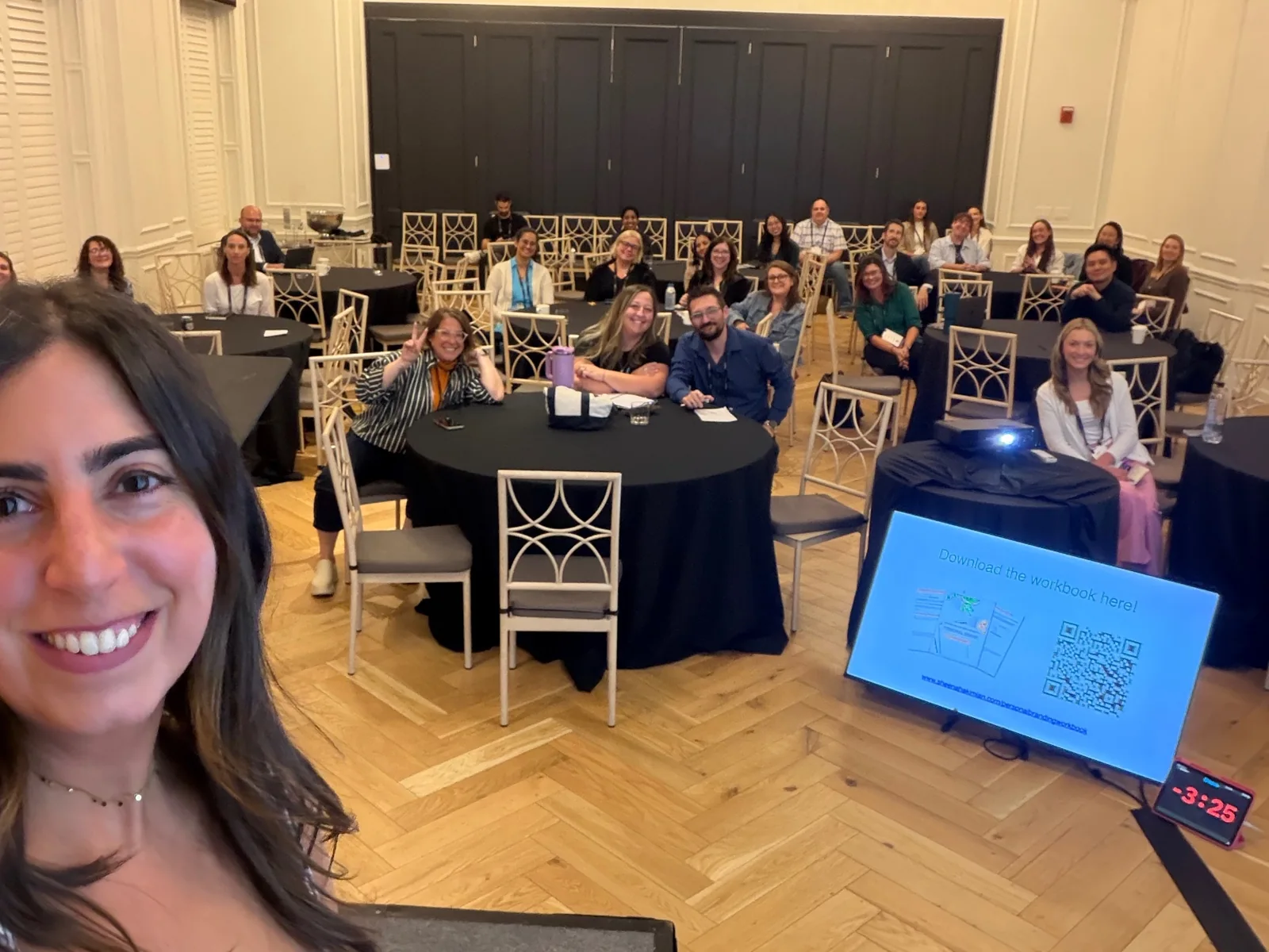 Sheena smiling with attendees at an in-person workshop